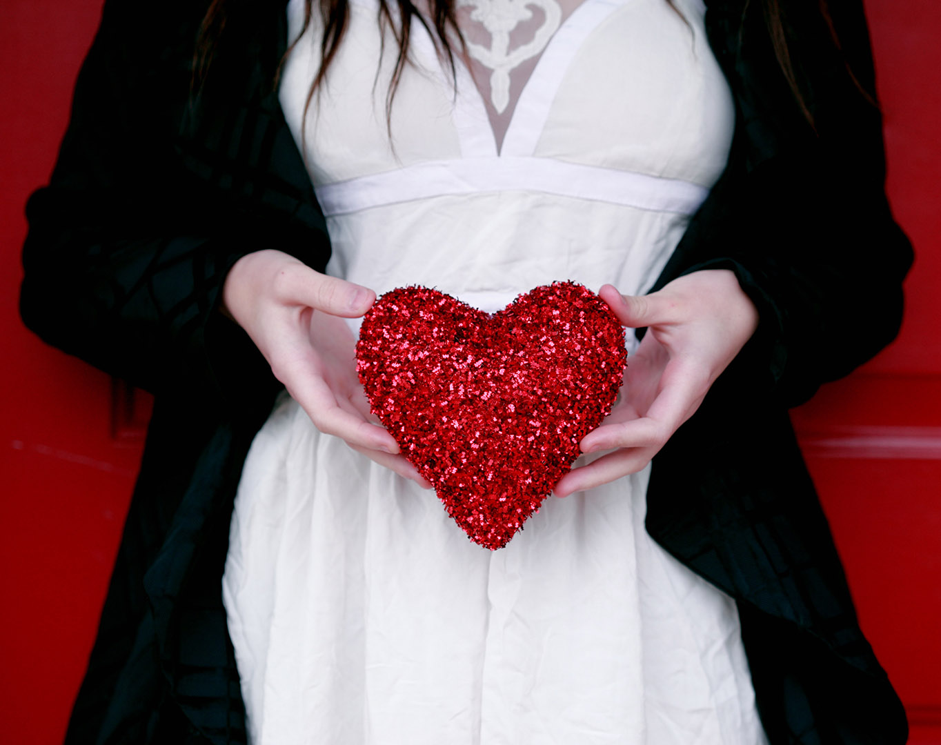 a woman wearing a dress holding a heart shaped item