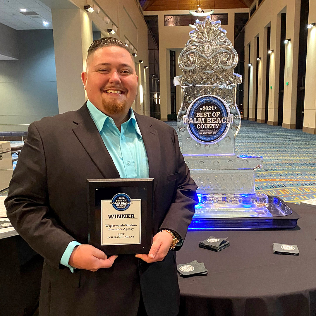 Insurance Agency, Kyle Cocchia, posing with a plaque and an ice sculpture at the best of palm beach award ceremony