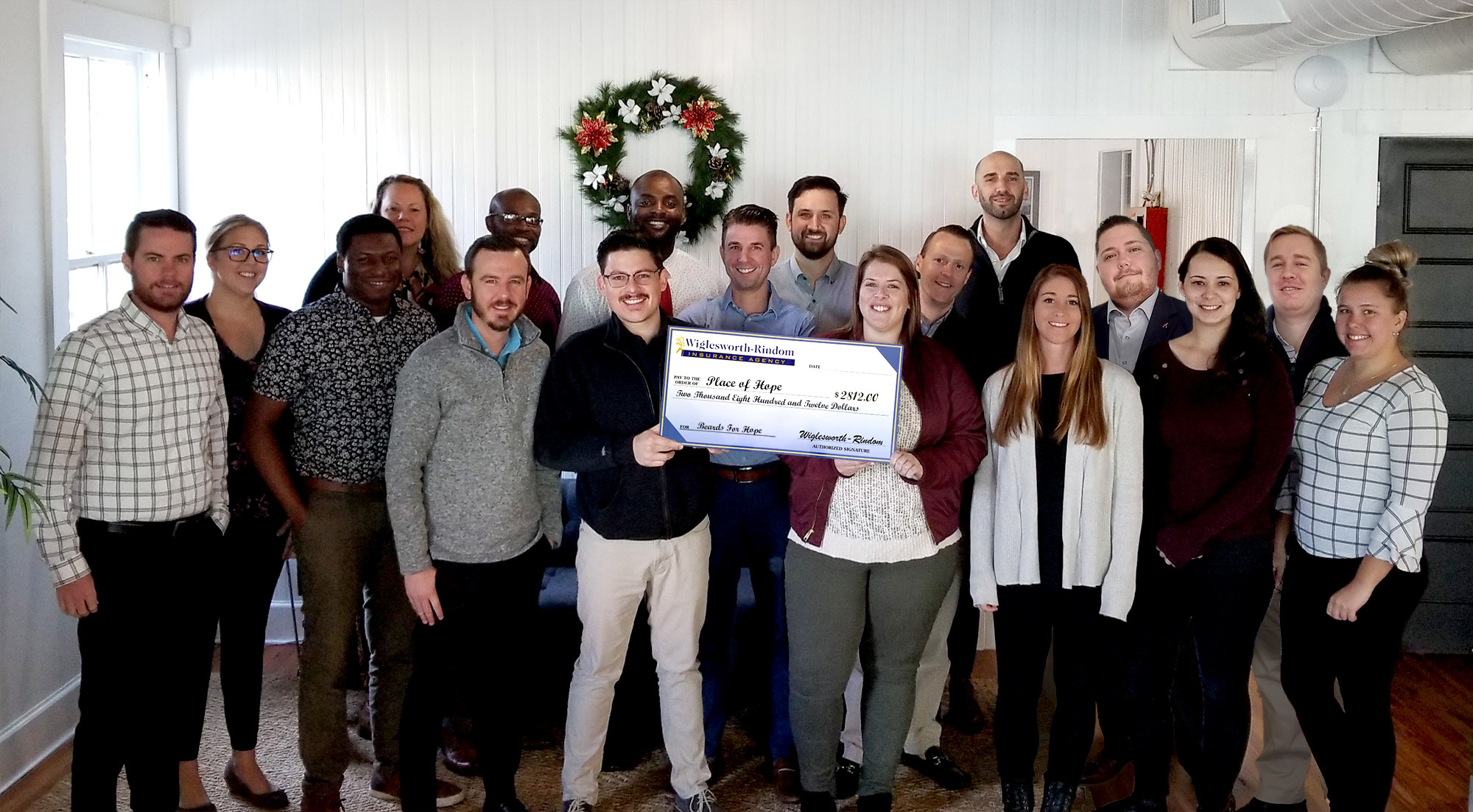 18 insurance agents standing around a large donation check