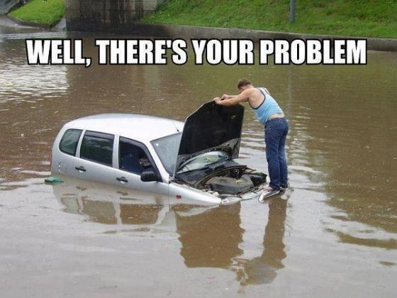 man checking engine in the middle of a flooded street