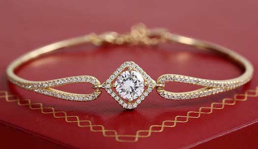 A Gold Bracelet with a diamond on a red table