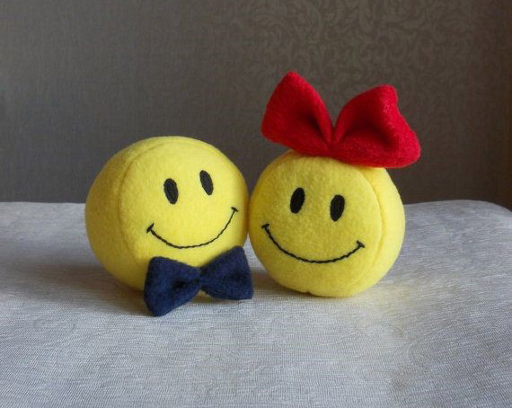 Two smiley face plushes one with a bowtie and another with a bow
