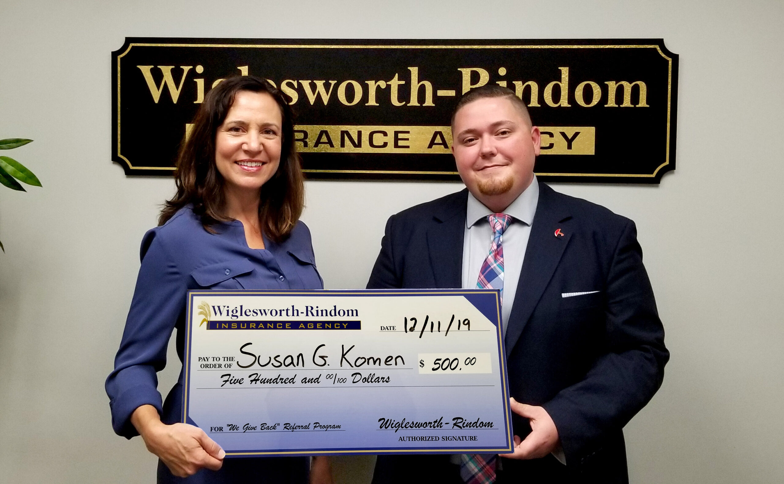 Natasha Moore holding a giant check with Insurance Agent Kyle Cocchia