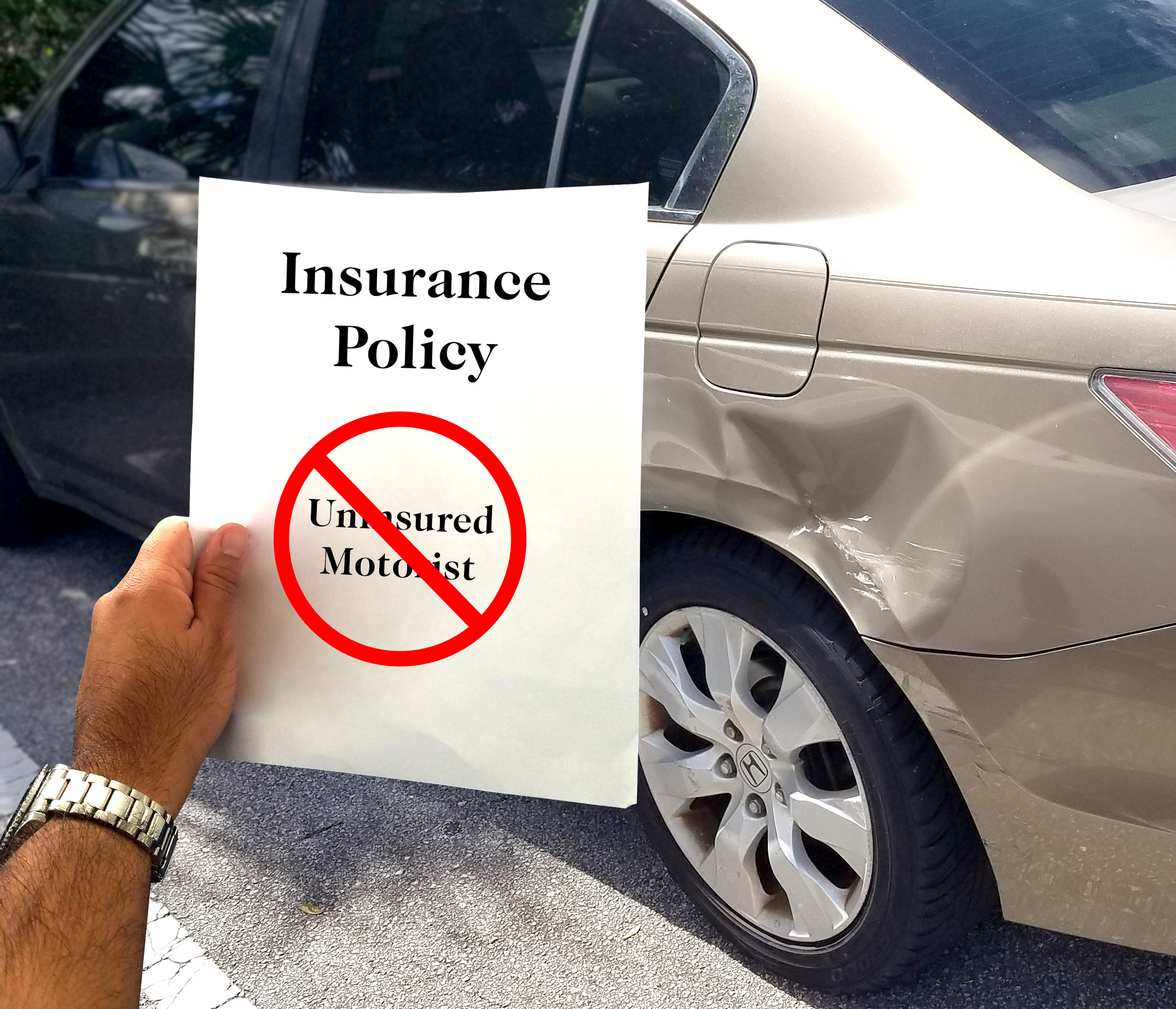 picture of paper with uninsured motorist on it with the word crossed out in front of a car with a dent in it.