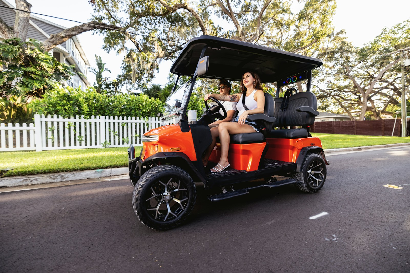 Two people riding a golf cart on a street